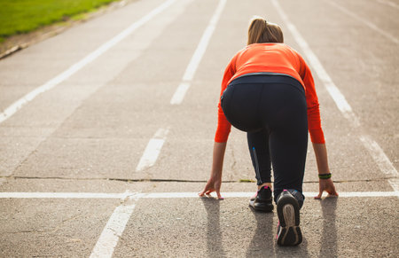 Young muscular athlete is at the start of the treadmill at the stadium.