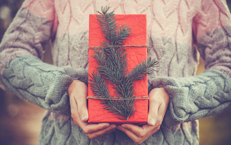 Female Holding Rustic Decorated Christmas Gift with tree branch
