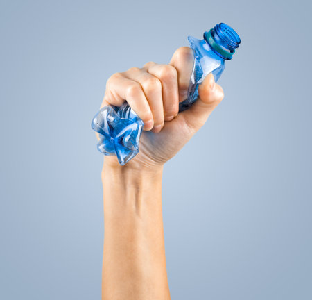 female hand squeezes an empty plastic bottleの写真素材