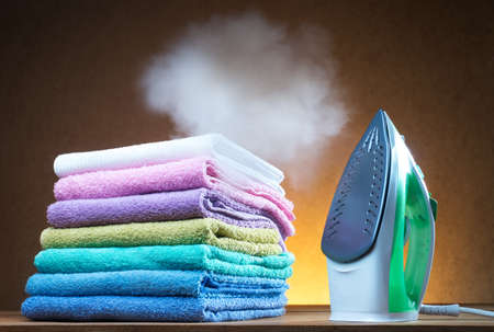 Green steaming iron with towels on the yellow backgroundの写真素材