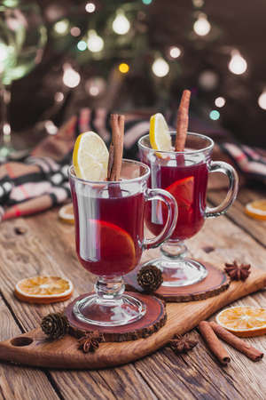 Mulled wine with cinnamon sticks and orange on the background of a christmas garlandの写真素材