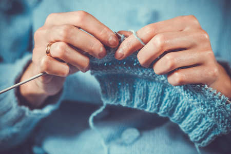close up the womans hands knitting a blue woolen sweaterの写真素材