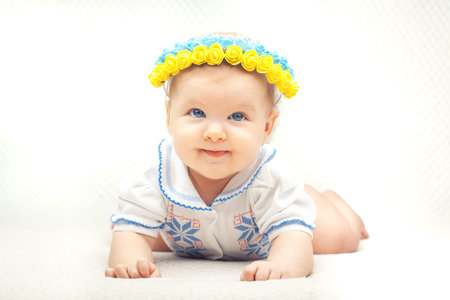 baby with flower wreath in the colors of the Ukrainian flag. six month old blue-eyed girl dressed in...