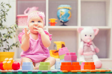 baby girl playing with colourful building blocks at home or kindergartenの写真素材