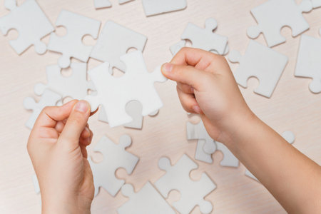 a child's hand makes the last missing piece of the puzzle on the table. strategy business conceptの写真素材