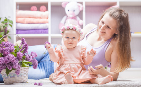 mother with a little daughter with a bouquet of lilacs in the children's roomの写真素材