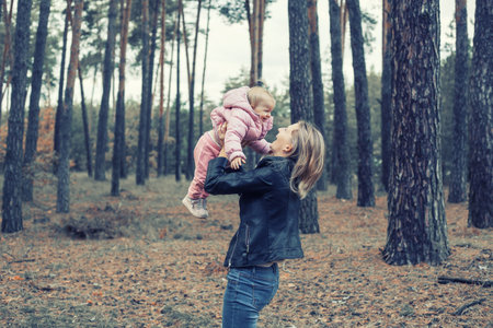 Family games in the autumn forest, mother throws the child upの写真素材