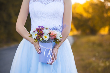 bride's hands with flowers on a background of autumn foliage. Bride with a bouquetの写真素材