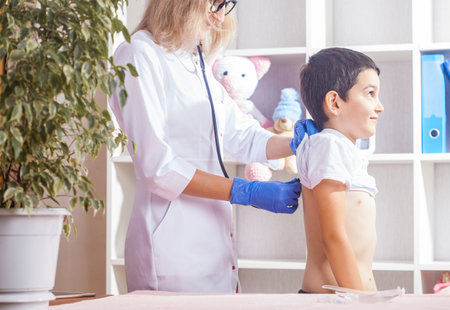 woman doctor or pediatrician with stethoscope listening to heartbeat boy's patient on medical exam at clinic. kid boy on medical examination checkupの写真素材