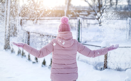Happy young woman plays with a snow in sunny winter day. Playing with snow on winter holidays, a...