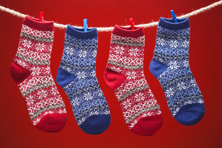 warm knitted socks on a rope on a red background. christmas concertの写真素材