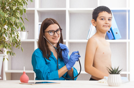 woman doctor or pediatrician with stethoscope listening to heartbeat boy's patient on medical exam at clinic. kid boy on medical examination checkupの写真素材