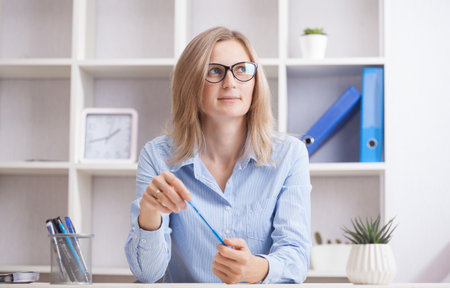 Young beautiful businesswoman sitting in a chair at her working place.の写真素材
