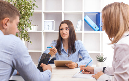 Attractive brunette businesswoman, teacher or mentor coach speaking to young people, young woman teaching audience at training seminar, female business leader speaker talking at meetingの写真素材