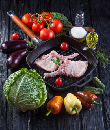 raw pork meat on the bone grill pan with fresh vegetablesの写真素材
