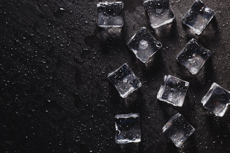 Pieces of ice cubes with water drops on black background. advertising photoの写真素材