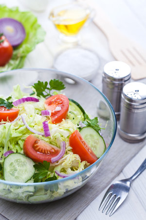 fresh spring salad of vegetables on a white wooden table.の写真素材