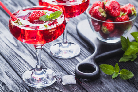 strawberry cocktail with ice and fresh mint on a black wooden tableの写真素材