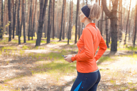 young girl on a morning run in a sunny pine forest. cardio workout and healthy lifestyleの写真素材