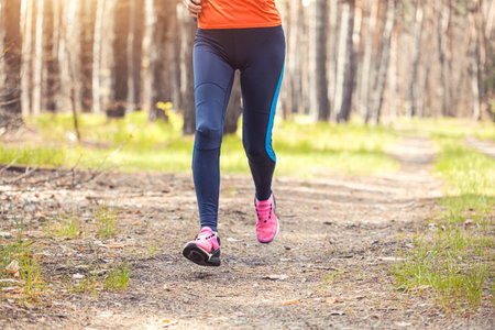 women athlete running through the woods. Feet, bottom viewの写真素材