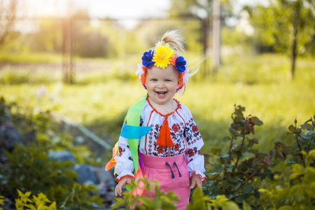 cute cheerful little girl in national Ukrainian clothes in a sunny summer gardenの写真素材