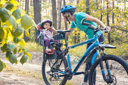 mother with small baby on bicycle. Family biking in the summer pine forestの写真素材