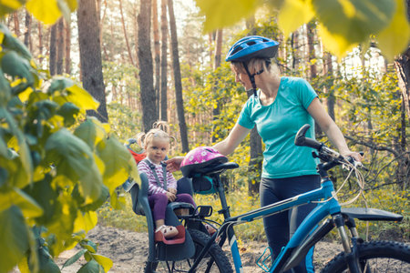 mother with small baby on bicycle. Family biking in the summer pine forestの写真素材
