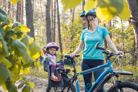 mother with small baby on bicycle. Family biking in the summer pine forestの写真素材