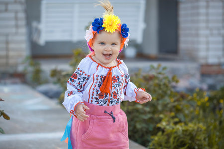 cute cheerful little girl in national Ukrainian clothes in a sunny summer gardenの写真素材
