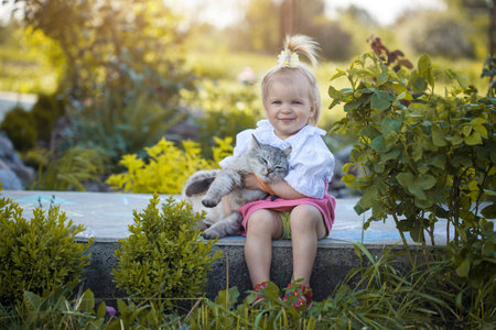 little baby with her cat in the summer gardenの写真素材