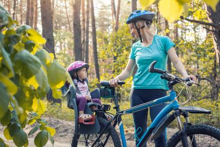 mother with small baby on bicycle. Family biking in the summer pine forestの写真素材