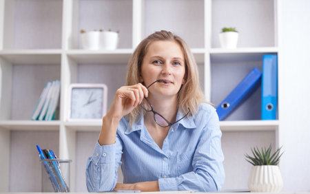 Young beautiful businesswoman sitting in a chair at her working place.の写真素材