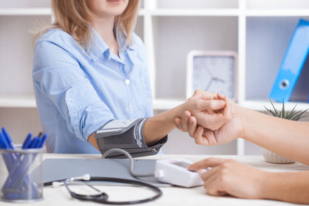 man doctor measures blood pressure in his office. scheduled medical examinationの写真素材