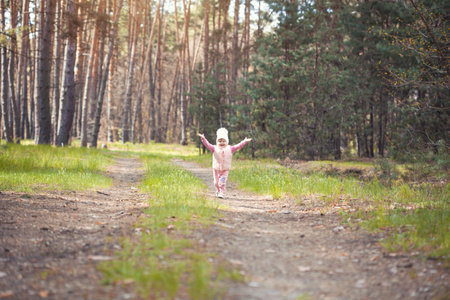 blue-eyed girl baby in a white hat walks in the spring forestの写真素材