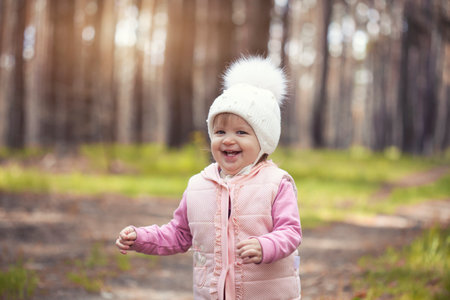 blue-eyed girl baby in a white hat walks in the spring forestの写真素材