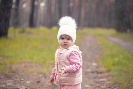 blue-eyed girl baby in a white hat walks in the spring forestの写真素材
