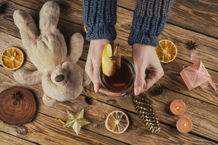 female hands with a hot cup of tea on a decorated wooden backgroundの写真素材