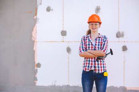 Insulation of the house with polyfoam. The female worker stands in front of a wall insulated with foam plasticの写真素材