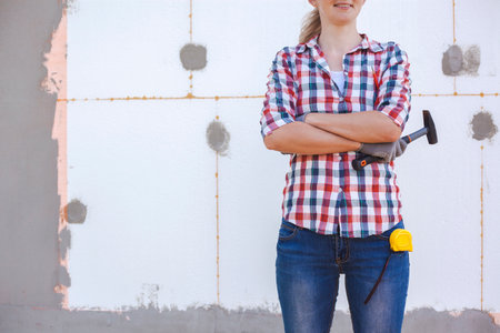 Insulation of the house with polyfoam. The female worker stands in front of a wall insulated with foam plasticの写真素材