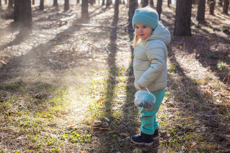 blue-eyed girl baby in a green hat walks in the pine spring forestの写真素材