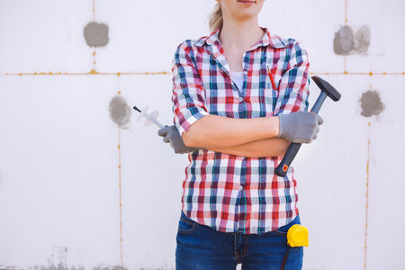 Insulation of the house with polyfoam. The female worker stands in front of a wall insulated with foam plasticの写真素材