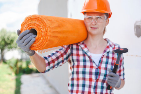 The woman with rolls of reinforcing fiberglass. Insulation of the house with polyfoam board on the facadeの写真素材