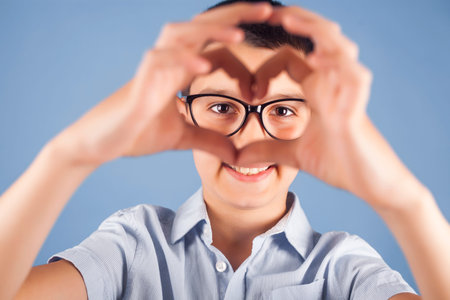 Portrait of happy kid join hands forming heart shape as concept of giving love. cute boy looking at...