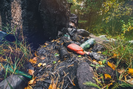 waste oil, empty plastic bottles, car battery, oil filter. A lot of harmful debris scattered in a green, pristine forestの写真素材
