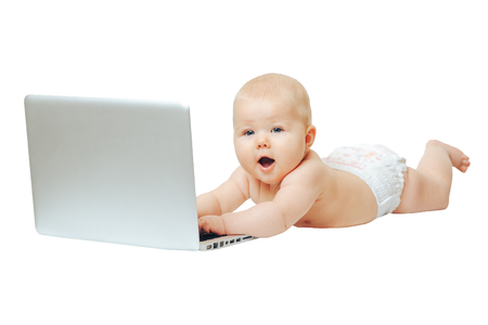Happy little baby lying naked in front of a silver laptop and presses a button.の写真素材