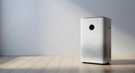 A sleek, white air purifier with a circular vent is positioned on a light-colored wooden floor, with soft light and shadows falling on a plain wall.の素材