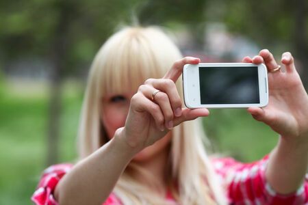 Pretty young blonde photographer in green parkの写真素材