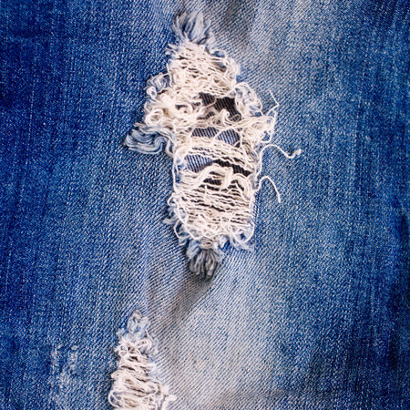 A closeup picture of a part of the jeans that is a bit tornの写真素材