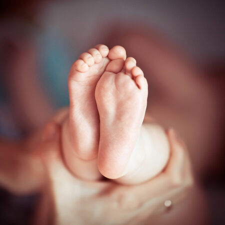 Newborn baby feet in mother handsの写真素材