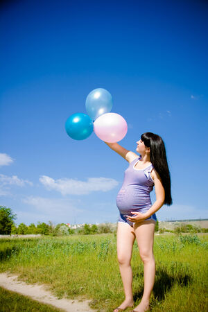 beautiful pregnant woman on a meadow with blue skyの写真素材